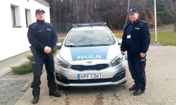 dwaj policjanci stoją przy radiowozie