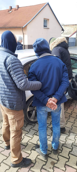 dwaj policjanci prowadzą zatrzymanego