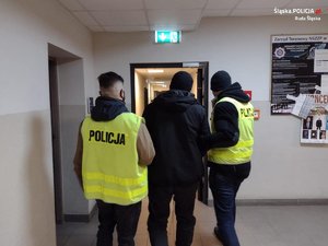 dwaj policjanci prowadzą zatrzymanego mężczyznę