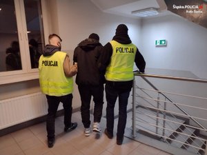 dwaj policjanci prowadzą zatrzymanego mężczyznę