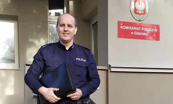 policjant przed budynkiem komisariatu