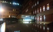 na tle budynku szpitalnego znajduje się radiowóz z umieszczonym na dachu świetlnym napisem