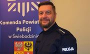 umundurowany policjant pozuje do zdjęcia na tle banera z napisem Komenda Powiatowa Policji w Świebodzinie