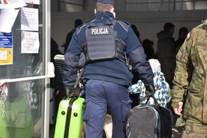 Policjant pomaga wnieść bagaż do hali