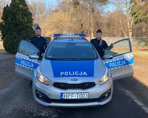 policjant i policnatka stoją przy radiowozie