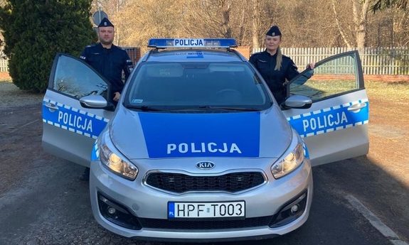 policjant i policnatka stoją przy radiowozie