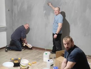 Trzech mężczyzn szykuje się do malowania ścian w pokoju