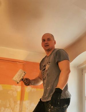 Mężczyzna na drabinie maluje sufit w pomieszczeniu