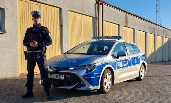 policjant stoi przy radiowozie