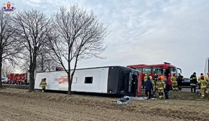 przewrócony autokar leży w rowie, obok stoją strażacy