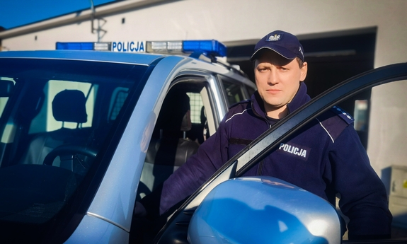 policjant stoi przy radiowozie