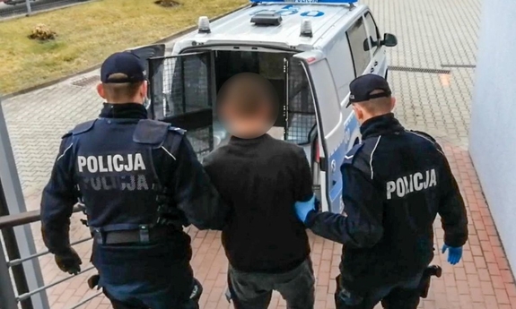 dwaj policjanci prowadzą zatrzymanego mężczyznę