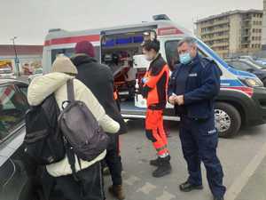 policjant i ratownicy medyczni przy karetce i inne osoby