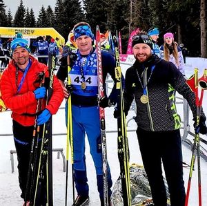 trzej mężczyźni z nartami w rękach i z medalami na szyi