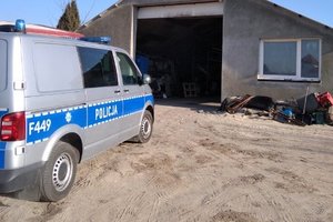 policyjny radiowóz przed garażem warsztatu samochodowego