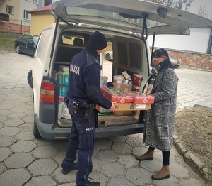policjant z koleżanką z pracy zanoszą zakupione towary do samochodu