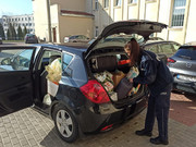 policjant wypakowuje z  samochodu dary zebrane dla uchodźców