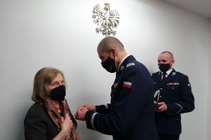 Zastępca Komendanta Głównego Policji przypina medal Prezes Fundacji PZU, z boku widać umundurowanego policjanta