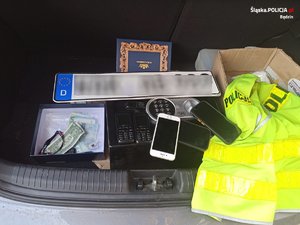 Zatrzymane przez policjantów rzeczy, które są w bagażniku samochodu : telefony, pieniądze, sejf, tablice rejestracyjne