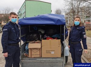 dwoje policjantów biorących udział w zbiórce przy przyczepce ze zgromadzonymi przedmiotami