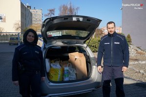 Komendant i policjantka na tle radiowozu z darami dla mieszkańców Ukrainy