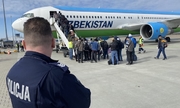 policjant w niebieskim mundurze obserwuje pasażerów wsiadających do samolotu
