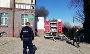 policjant i strażacy, wóz strażacki przy budynku w którym wybuchł pożar