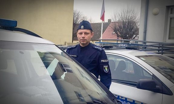 Policjant stojący przy radiowozach policyjnych