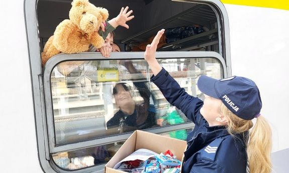 policjantka przybija piątkę przez okno w wagonie z chłopcem, w oknie widać pluszowego misia