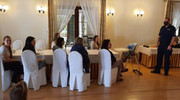 Podkomisarz Rafał Goc podczas spotkania z uchodźcami. Na zdjęciu widoczne kobiety, które siedzą przy stole