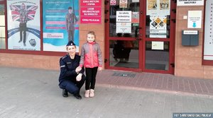 policjantka z dziewczynką przed budynkiem szkoły