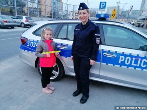 policjantka stoi z dziewczynką przy radiowozie