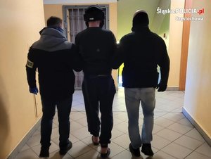 dwaj policjanci prowadzą zatrzymanego mężczyzny