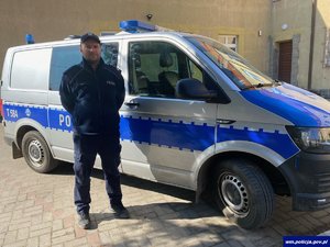 umundurowany policjant stoi przy radiowozie