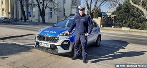 umundurowany policjant stoi przy radiowozie