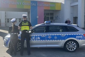 Dwoje policjantów stoi przed radiowozem - widok z tyłu