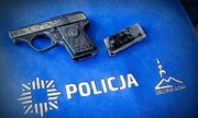Zabytkowy pistolet na niebieskiej torbie z napisem Policja