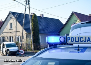 Radiowóz Policji. W tle rozbite w wyniku pościgu auto