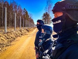 policjanci stoją przy płocie na granicy