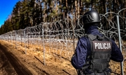policjant stoi naprzeciwko płotu na granicy