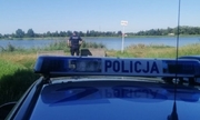 radiowóz policyjny w tle umundurowany policjant stoi nad rzeką