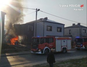 płonący budynek, obok stoi wóz straży pożarnej