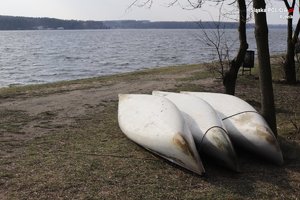 trzy kajaki leżące na brzegu zbiornika wodnego, odwrócone dnem do góry