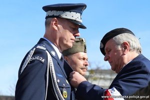 mężczyzna przypina odznaczenie komendantowi wojewódzkiemu Policji we Wrocławiu