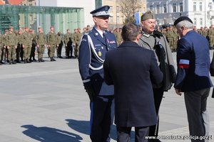 komendant wojewódzki Policji we Wrocławiu stoi na placu z mężczyzną ubranym w stój wojskowy z czasów II wojny światowej oraz dwaj mężczyźni, w tle żołnierze