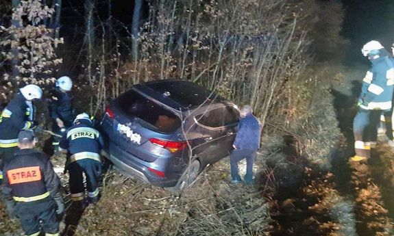 Samochód stojący w rowie, a obok niego strażacy