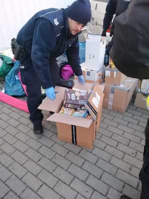 policjant pochyla się nad odzyskanymi darami z kradzieży dla uchodźców