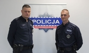 dwaj policjanci na tle baneru z napisem policja