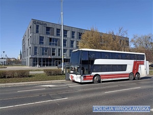 Autobus stojący na jezdni na tle budynku komisariatu na Krzykach