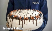 policjantka trzyma tort przygotowany przez kobietę w podziękowaniu za odzyskanie skradzionej torebki